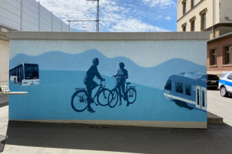 Blaues Wandbild auf dem zwei Fahrradfahrer, eine Regionalbahn und ein Linienbus gesprüht wurde