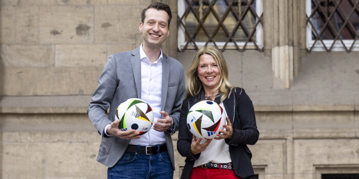 ein Mann und eine Frau halten jeweils einen Fußball