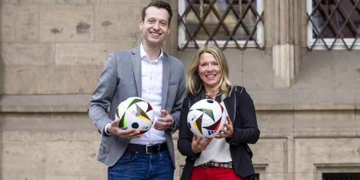 ein Mann und eine Frau halten jeweils einen Fußball