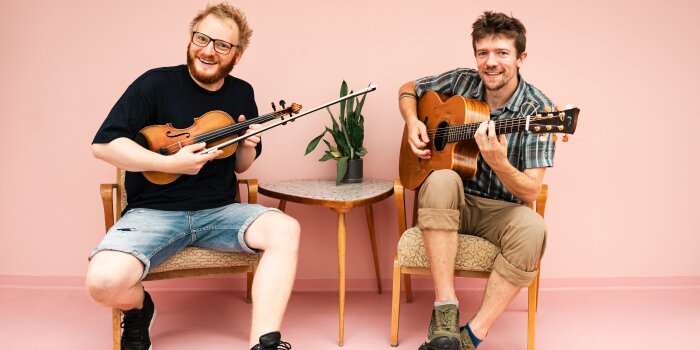 zwei Männer, einer mit Violine, einer mit Gitarre