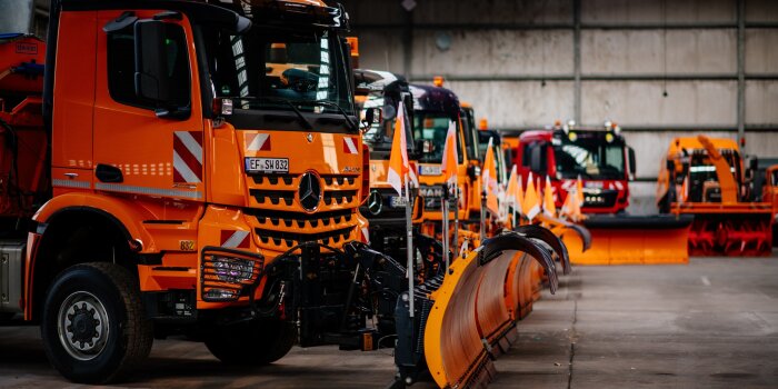 Mehrere große, orangfarbene Winterdienstfahrzeuge 