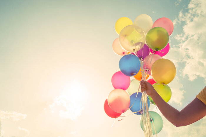 Hand mit bunten Ballons vor Himmel