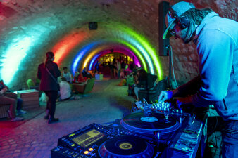 DJ unter Steinbogen mit buntem Licht 
